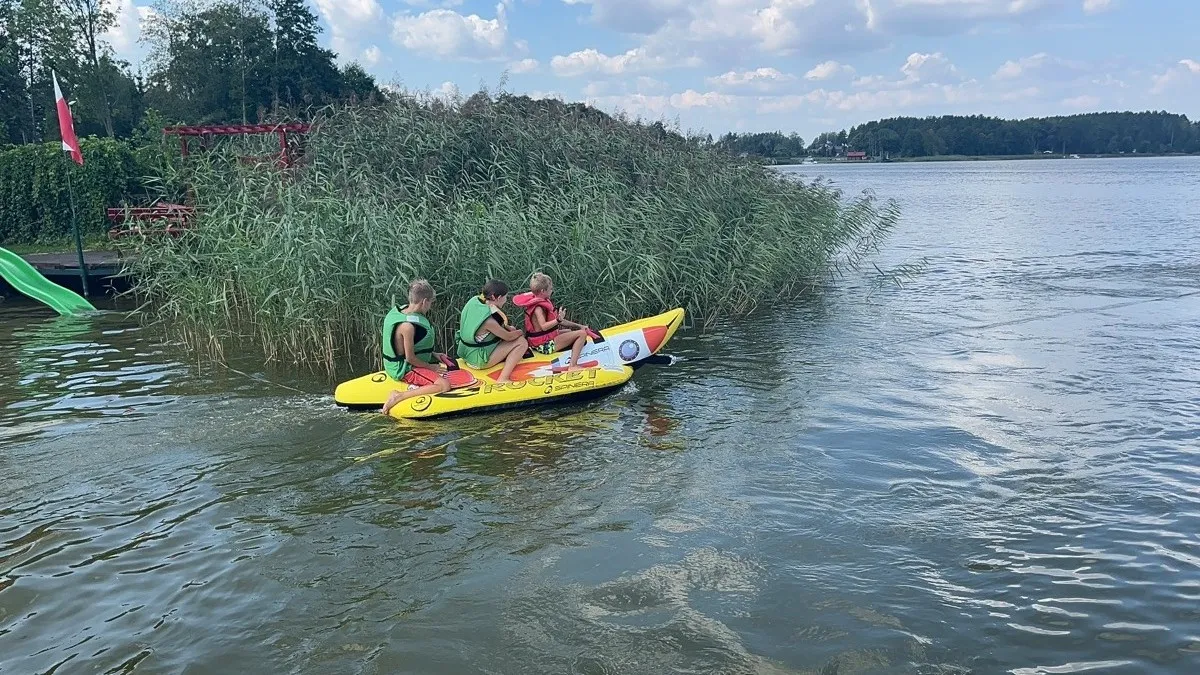 Dzieci na bananie za motorówką na jeziorze Necko