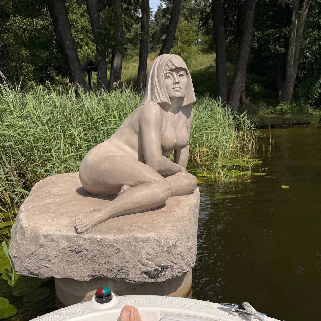 Sandsteinskulptur einer sitzenden Frau auf einem Findling an der Rospuda bei Augustów